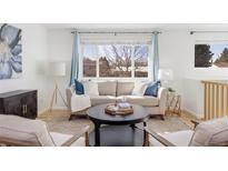 Bright living room featuring a cozy sofa, stylish decor, and a large window with natural light at 12579 E Alaska Pl, Aurora, CO 80012