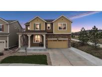 Charming two-story home featuring a two-car garage, covered porch, and manicured front lawn at dusk at 19760 W 59Th Dr, Golden, CO 80403