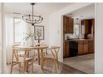 Bright dining area features wood table and chairs, modern lighting, and view into the kitchen at 916 Florence St, Aurora, CO 80010