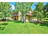 Spacious backyard featuring a two-story house, lush green lawn, and beautiful birch trees at 19235 Wakonda Way, Monument, CO 80132