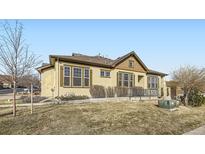 Tan single Gathering home with well-manicured lawn and brown trim windows on a sunny day at 11925 W Ida Dr, Littleton, CO 80127