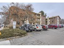 A view of a brick condominium building with a parking lot in front of it on a cloudy day at 1358 S Irving St # 53, Denver, CO 80219