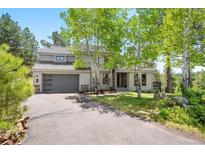 Charming two-story home featuring a two-car garage, mature trees, and manicured landscaping at 2122 Cramner Ct, Evergreen, CO 80439