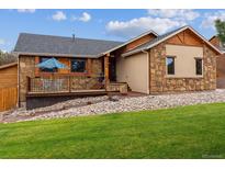 Charming home features a stone and wood facade, a deck, and a well-manicured lawn at 8966 Sunridge Hollow Rd, Parker, CO 80134