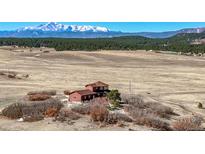 Expansive exterior view of the red home with mountain range in the background at 4586 Best Rd, Larkspur, CO 80118
