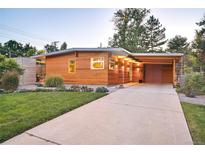 Mid-century modern home with wood siding, landscaped lawn, and attached garage at 1497 S Fairfax St, Denver, CO 80222