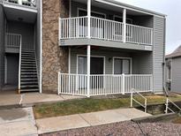 Condo with a stone column accent, white fencing, gray siding and balconies at 910 S Walden St # 101, Aurora, CO 80017