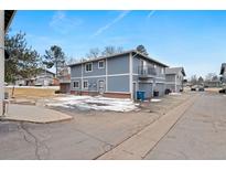 Two-story townhome with blue siding, individual garages, and ample parking space in a well-maintained community at 1289 S Wheeling Way, Aurora, CO 80012