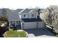 Charming two-story home featuring a covered porch, a three-car garage, and a well-manicured lawn at 5654 S Zante Cir, Aurora, CO 80015