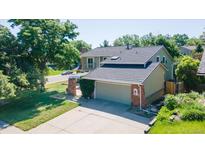 Two-story home boasts a neutral exterior, well-manicured lawn, large driveway, and attached two-car garage at 7118 W Elmhurst Ave, Littleton, CO 80128