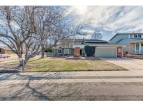 Inviting two-story home featuring a well-kept lawn, mature trees, and a convenient two-car garage at 7118 W Elmhurst Ave, Littleton, CO 80128