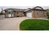 Charming brick home featuring a well-maintained lawn, spacious driveway, and an attached two-car garage at 2151 Burbank St, Berthoud, CO 80513