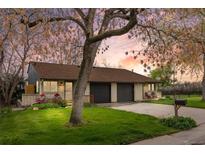 Charming brick home with a well-manicured lawn, mature trees, and a cozy front porch at 1002 Zang St, Golden, CO 80401