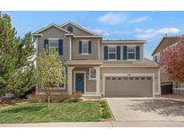 Charming two-story home featuring a manicured lawn, inviting blue door, and an attached two-car garage at 1558 Wandering Way, Castle Rock, CO 80109