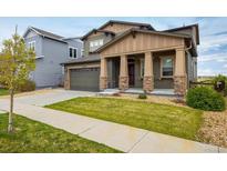 Charming two-story home with a well-manicured lawn, covered porch with stone accents, and an attached two-car garage at 14807 Haley Ave, Parker, CO 80134