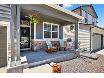 Charming front porch featuring decorative chairs, hanging flower baskets, and a welcoming entrance at 635 Silver Rock Trl, Castle Rock, CO 80104