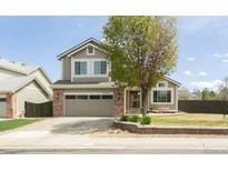 Charming two-story home with a well-manicured lawn, mature tree, and a two-car garage at 9768 Otis Dr, Broomfield, CO 80021