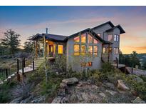Stunning exterior view of a multi-story home, complemented by mature trees and natural rock outcroppings at 23007 Big Game Trl, Conifer, CO 80433