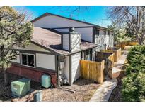 Exterior view of home featuring gray siding, brick accents, well maintained yard and a private, fenced patio at 15157 E Louisiana Dr # A, Aurora, CO 80012