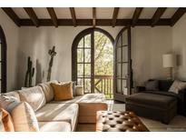 Inviting living room featuring exposed beam ceiling, comfortable seating, and natural light from the arched window at 3 Carriage Brook Rd, Cherry Hills Village, CO 80121