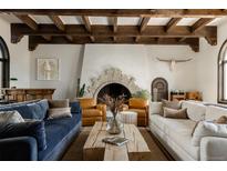 A comfortable living room with a beamed ceiling and a fireplace, surrounded by a blue couch and leather chairs at 3 Carriage Brook Rd, Cherry Hills Village, CO 80121
