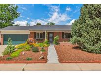 Charming brick home features a beautifully landscaped front yard with colorful flowers and mature trees at 3049 S Williams St, Denver, CO 80210
