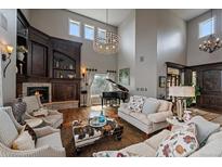 Elegant living room boasts high ceilings, a fireplace, and large windows providing natural light and backyard views at 1159 Buffalo Ridge Rd, Castle Pines, CO 80108