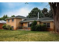 Charming brick home featuring mature trees, green lawn, and a cozy front porch at 2592 S Winona Ct, Denver, CO 80219