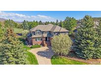 Stunning exterior view of this brick and wood home featuring mature trees and an elegant, winding driveway at 73 N Ranch Rd, Littleton, CO 80127
