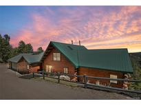 Stunning log home with a green metal roof and beautiful sunset views nestled in a serene natural setting at 10268 Christopher Dr, Conifer, CO 80433