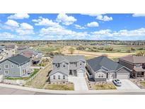Beautiful two-story home with gray siding, a well-manicured lawn, and a stunning mountain view in the background at 5736 Cadara Way, Parker, CO 80134