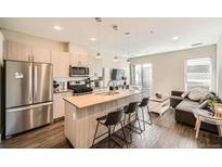 Modern kitchen with stainless steel appliances, island with seating, and open floor plan at 2374 S University Blvd # 204, Denver, CO 80210
