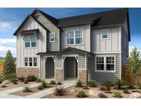 Charming two-story home featuring stone accents, gray siding, and a welcoming covered entryway at 13569 E 111Th Ave, Commerce City, CO 80022