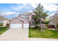 Stunning brick two-story home with a well-manicured lawn and a three car garage on a sunny day at 446 Angus Way, Highlands Ranch, CO 80129