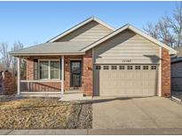 Charming single-Gathering home featuring a brick facade, covered porch, and a two-car garage at 11197 W 64Th Pl, Arvada, CO 80004