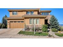 Two-story home featuring a tan stucco and stone facade with an attached two-car garage at 10751 Manorstone Dr, Highlands Ranch, CO 80126