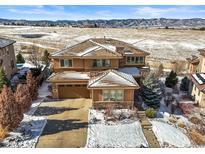 Stunning exterior with snow-dusted roof, lush landscaping, and mountain views at 10751 Manorstone Dr, Highlands Ranch, CO 80126