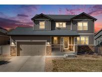 Beautiful two-story home featuring a two-car garage and a welcoming front porch with stone accents at 12017 Triple Crown Dr, Parker, CO 80134