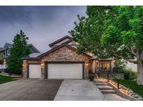 Charming two-story home featuring a stone facade, three-car garage, and meticulously landscaped front yard at 8657 Aberdeen Cir, Highlands Ranch, CO 80130