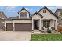 Charming home featuring a two-car garage, front porch with seating, and stucco siding accented by stone at 11511 E 118Th Ave, Commerce City, CO 80640