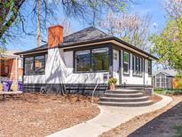 Charming home featuring black and white paint, a brick chimney, and beautiful landscaping at 2517 W 44Th Ave, Denver, CO 80211