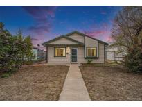 Charming single-story home with a well-manicured lawn and inviting front porch under a beautiful sunset sky at 124 3Rd St, Fort Lupton, CO 80621