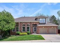 Charming two-story brick home featuring a well-manicured lawn, mature trees and an attached two-car garage at 9524 E Caley Cir, Englewood, CO 80111