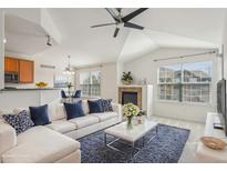 Bright living room featuring vaulted ceilings, a fireplace, and a large window overlooking the neighborhood at 1495 Blue Sky Way # 9-308, Erie, CO 80516