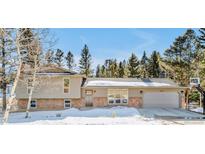 Charming single-Gathering home with stone accents, attached garage and snow covered yard at 30633 Kings Valley Dr, Conifer, CO 80433