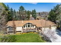 Stunning home featuring mature trees, lush landscaping, and a spacious deck perfect for outdoor living at 10395 W 74Th Pl, Arvada, CO 80005