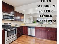 Well-lit kitchen with stainless steel appliances, granite countertops and dark wood cabinets at 1095 W 69Th Ave, Denver, CO 80221