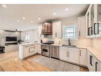 Bright kitchen with stainless steel appliances, white cabinetry, and stylish copper range hood at 519 S Gaylord St, Denver, CO 80209
