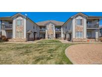 Well-maintained condo building with stone accents and lush green lawn under a clear blue sky at 3250 E 103Rd Pl # 805, Thornton, CO 80229