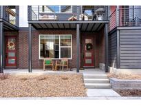 Inviting front porch with brick facade, rocking chairs, and stylish red door, offering a cozy curb appeal at 12193 W 51St Ave, Wheat Ridge, CO 80033